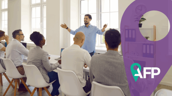 Man presents to colleagues in front of whiteboard, open arms for expression. Purple symbol and AFP logo on the right. Source Canva