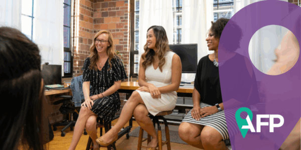 Women sitting on charis stalls in a circle inside a room, chatting and smiling